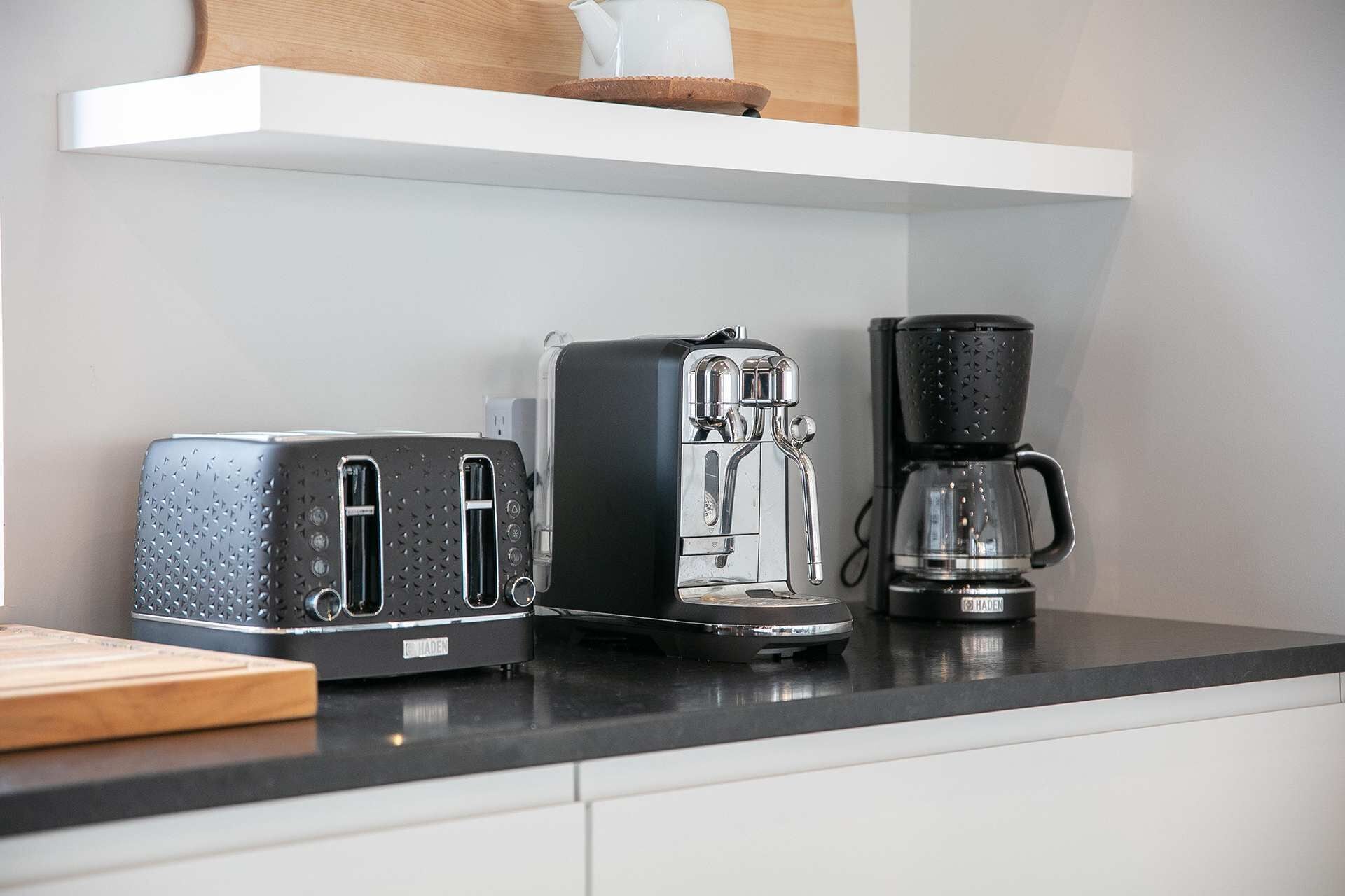 A kitchen counter with a toaster, a coffee maker, and a kettle.