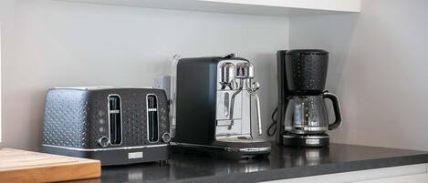 A kitchen counter with a toaster, a coffee maker, and a kettle.