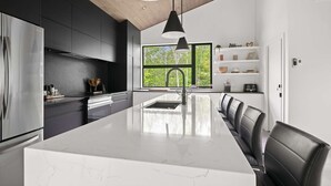 A modern kitchen with a large island, dark cabinetry, and a wooden ceiling. - Eastman - Spa - Zénitude (Eastman)