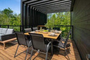 An outdoor dining area with a wooden table, chairs, and a sofa.