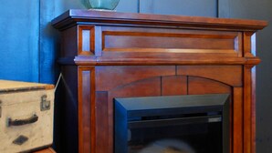 A fireplace with a mantel, a lamp, and stacked luggage against a blue wall. - Kinder Rm, The Lodge at  Old City Hall (Jefferson City)