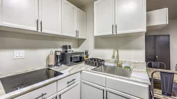 A compact kitchen with white cabinets, a stainless steel sink, a coffee maker, and a microwave.