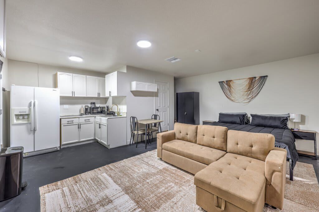 A modern apartment with a kitchenette, a sofa, a bed, and a dining area.
