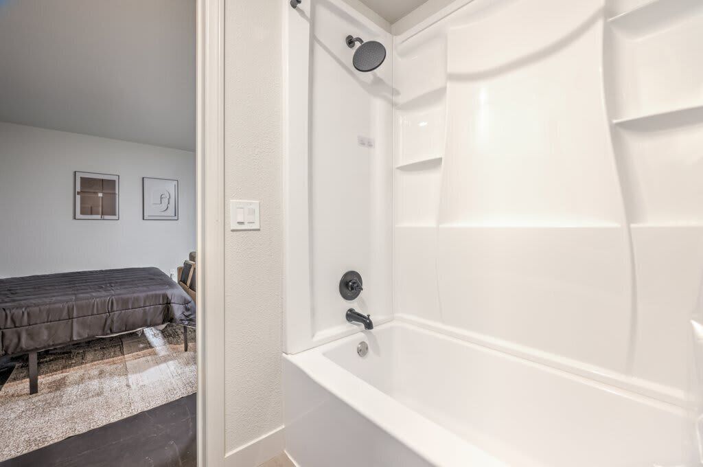 A modern bathroom with a white bathtub and shower.