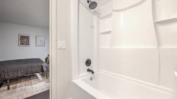 A modern bathroom with a white bathtub and shower.