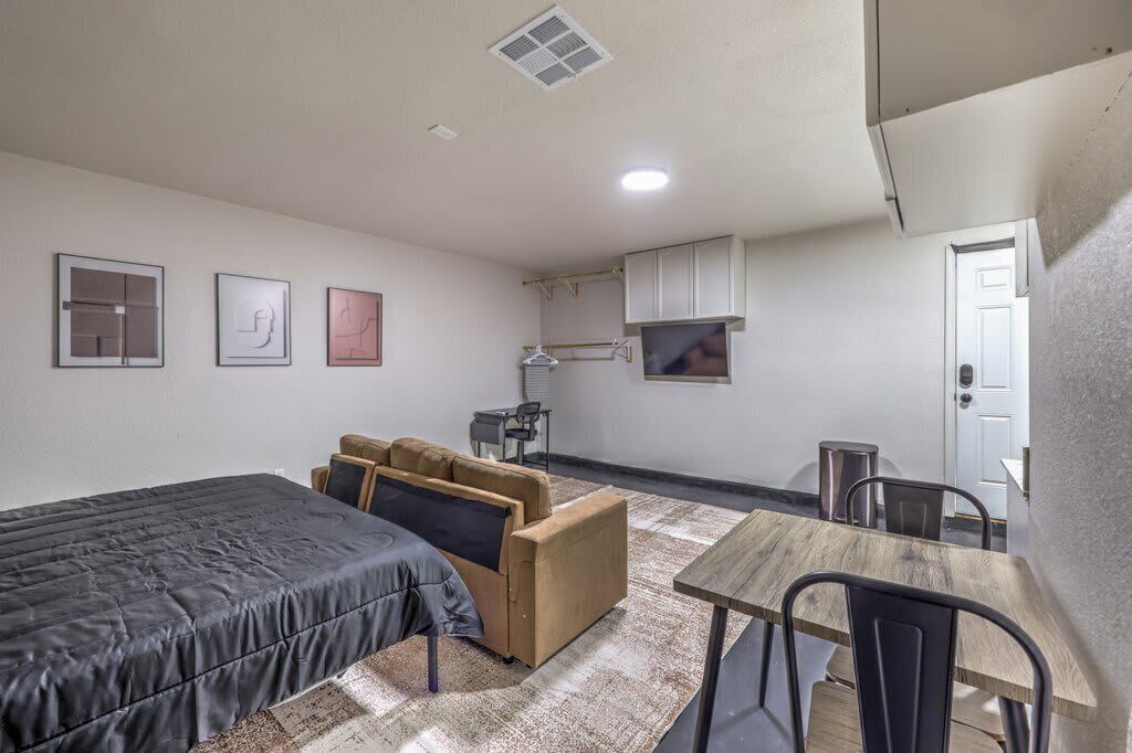 A compact room with a bed, a sofa, a small table, and a kitchenette.