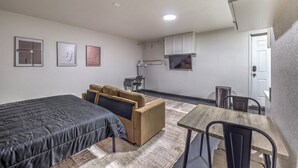 Une pièce de taille modeste comprenant un lit, un canapé, une petite table et un coin cuisine.