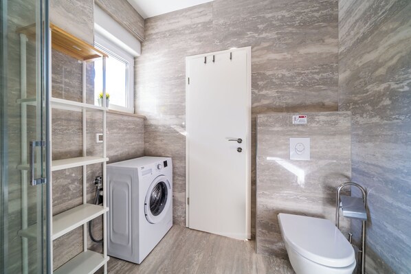 Un baño pequeño con lavadora, inodoro y una puerta con señal de seguridad.