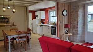Une cuisine moderne avec des meubles blancs, un coin repas rouge et une grande fenêtre.
