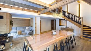 Een ruime woonkamer met een houten eettafel, een trap en een gezellige zithoek.