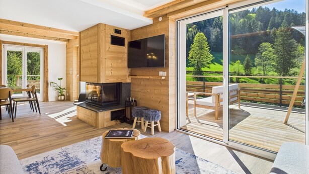 Een modern interieur met een houten chaletstijl, een open haard, een eetgedeelte en een balkon met een prachtig uitzicht.