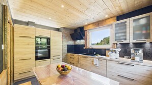 Een moderne keuken met houten kastjes, een inbouwoven, een magnetron en een koffieapparaat.