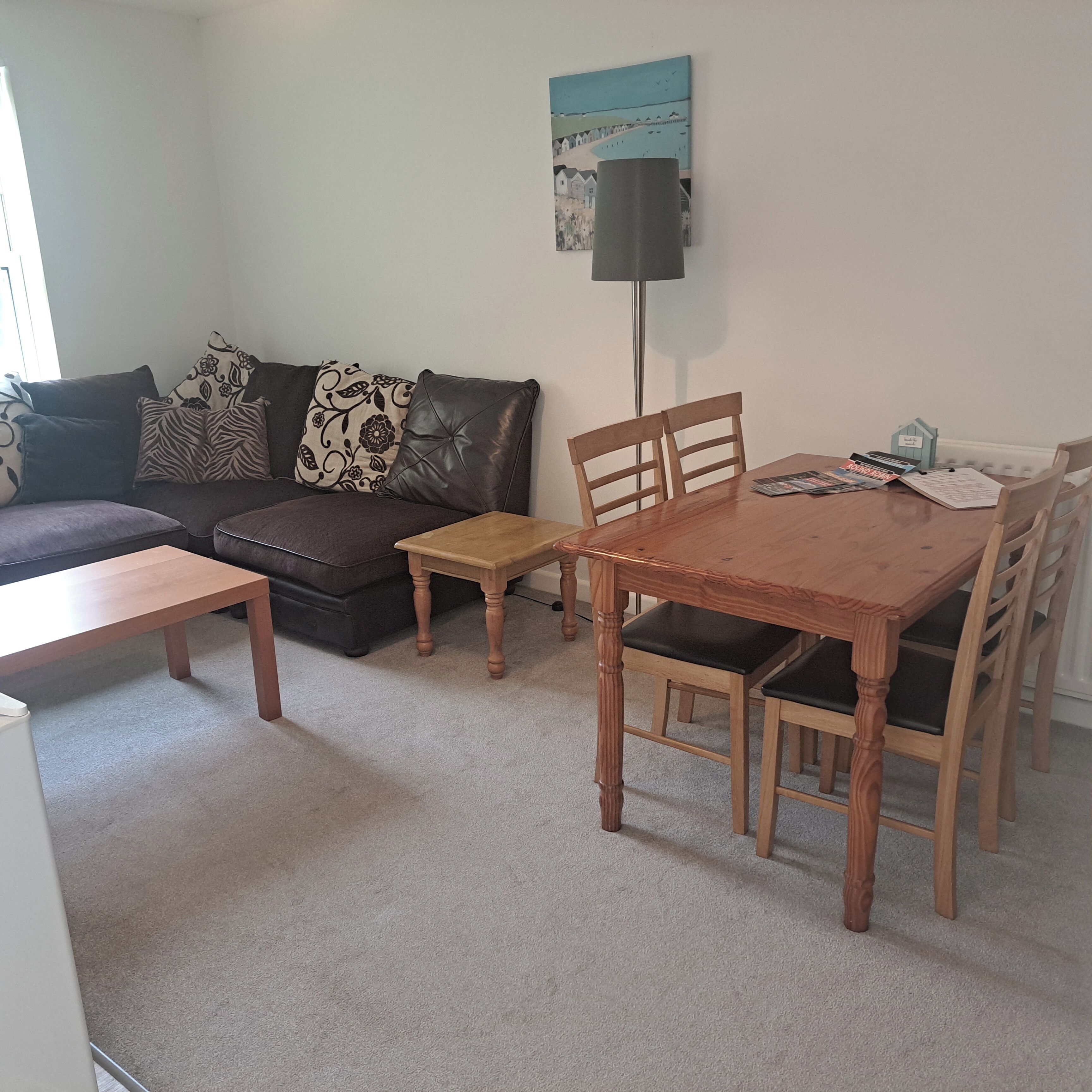 A living room with a sofa, a coffee table, a dining table with chairs, and a lamp.