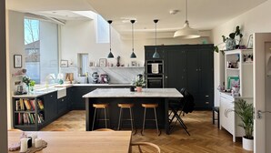 A modern kitchen with a marble countertop, dark cabinets, and pendant lighting. - Bright Spacious 5-bedroom house in Dundrum with sunken Trampoline and Treehouse. (Dublin 8)