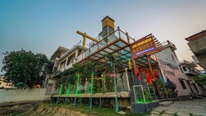 A hotel with a glass facade, a sign reading "Rudraksh Shiv Resort," and a balcony with railings. - Shiv Rudraksh Resort - Near Assi Ghat (Varanasi)