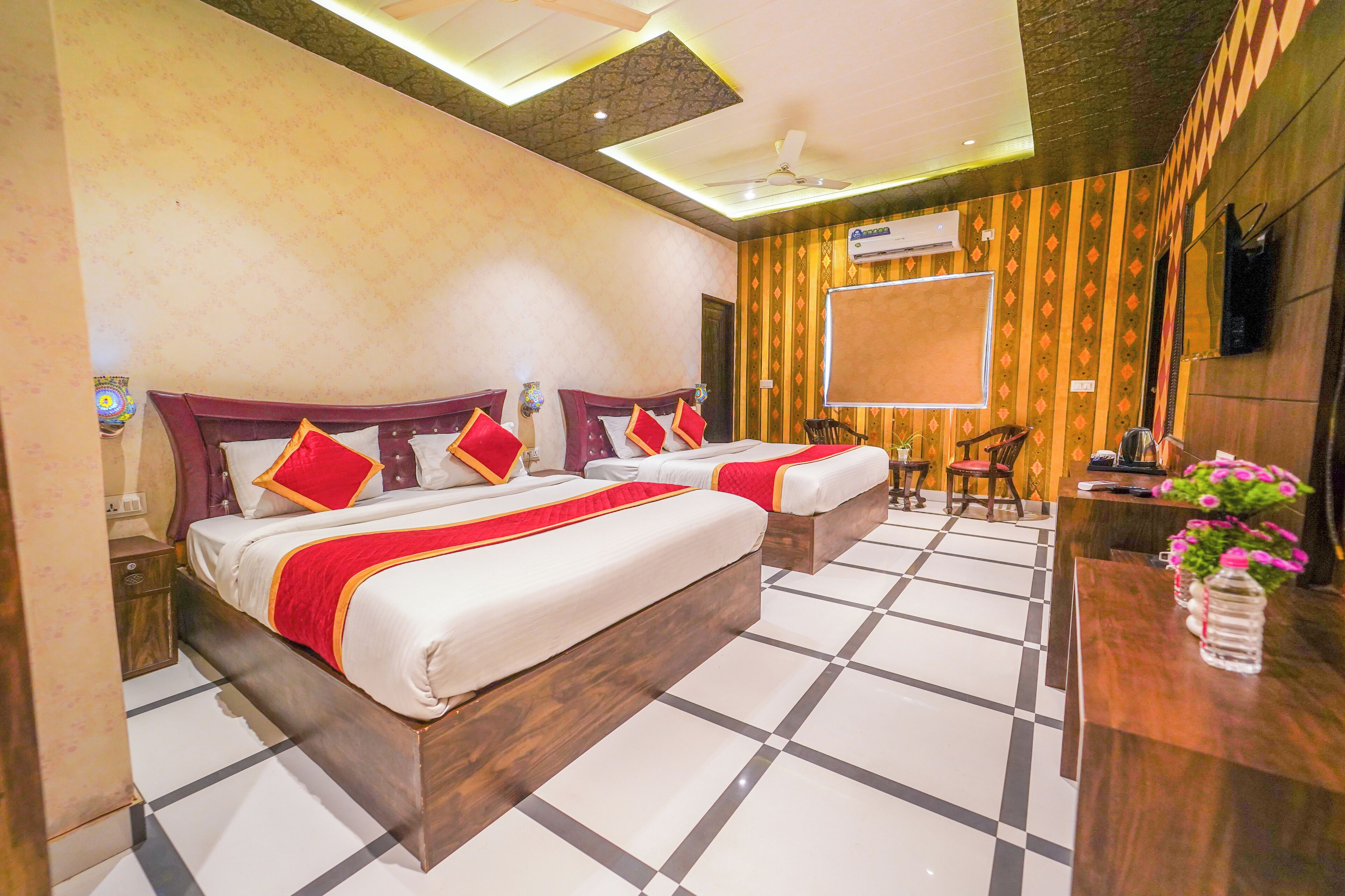 A hotel room with two beds, a desk, and a TV.
