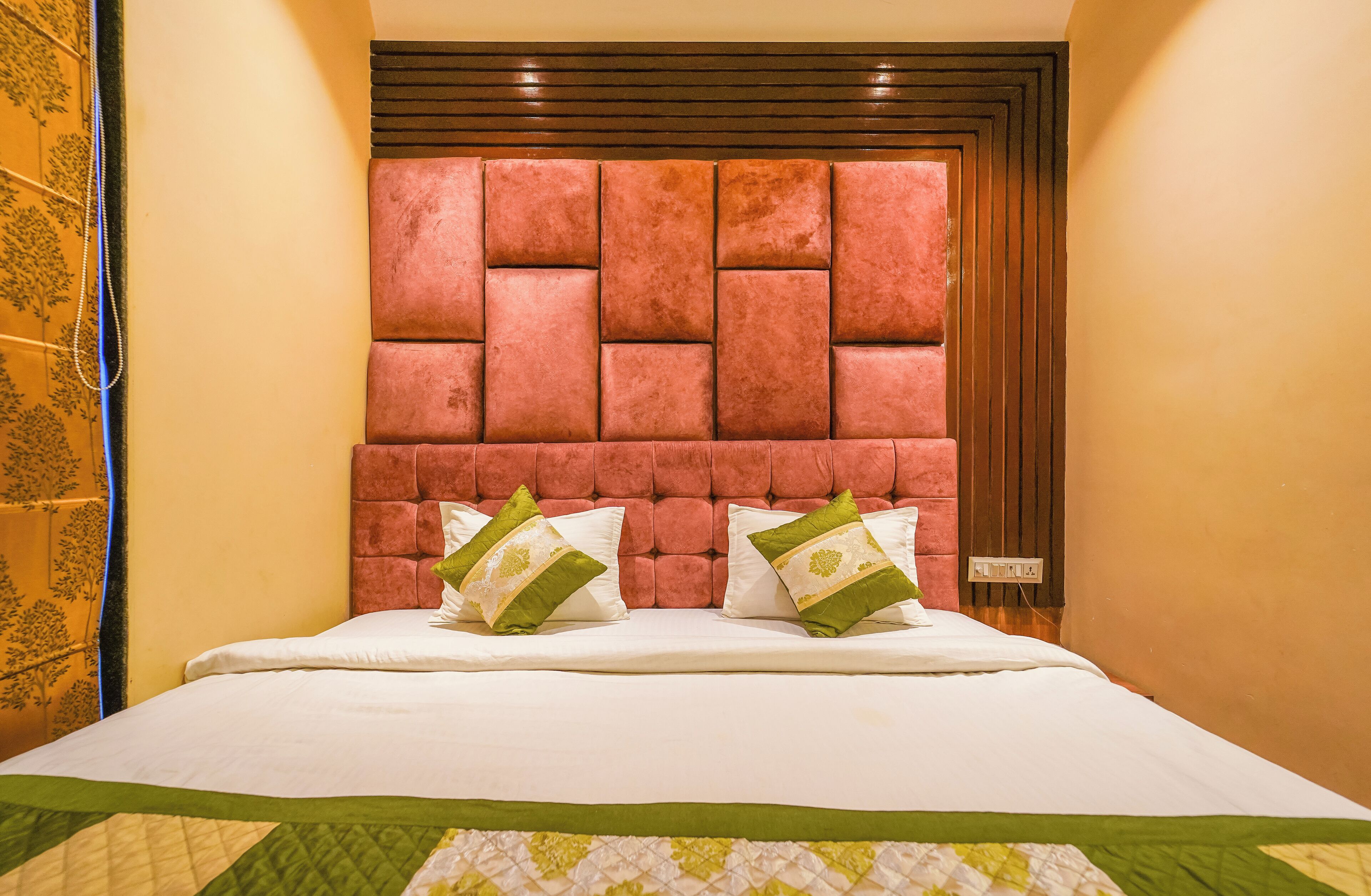 Una habitación de hotel con una cama grande, un cabecero de madera y un edredón verde y blanco.