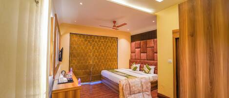 Quarto de hotel moderno com cama, escrivaninha, cadeira e ventoinha no teto.