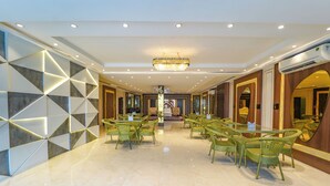 A spacious hotel lobby with a central seating area, a chandelier, and a modern design with geometric wall patterns. - Shiv Rudraksh Resort - Near Assi Ghat (Varanasi)