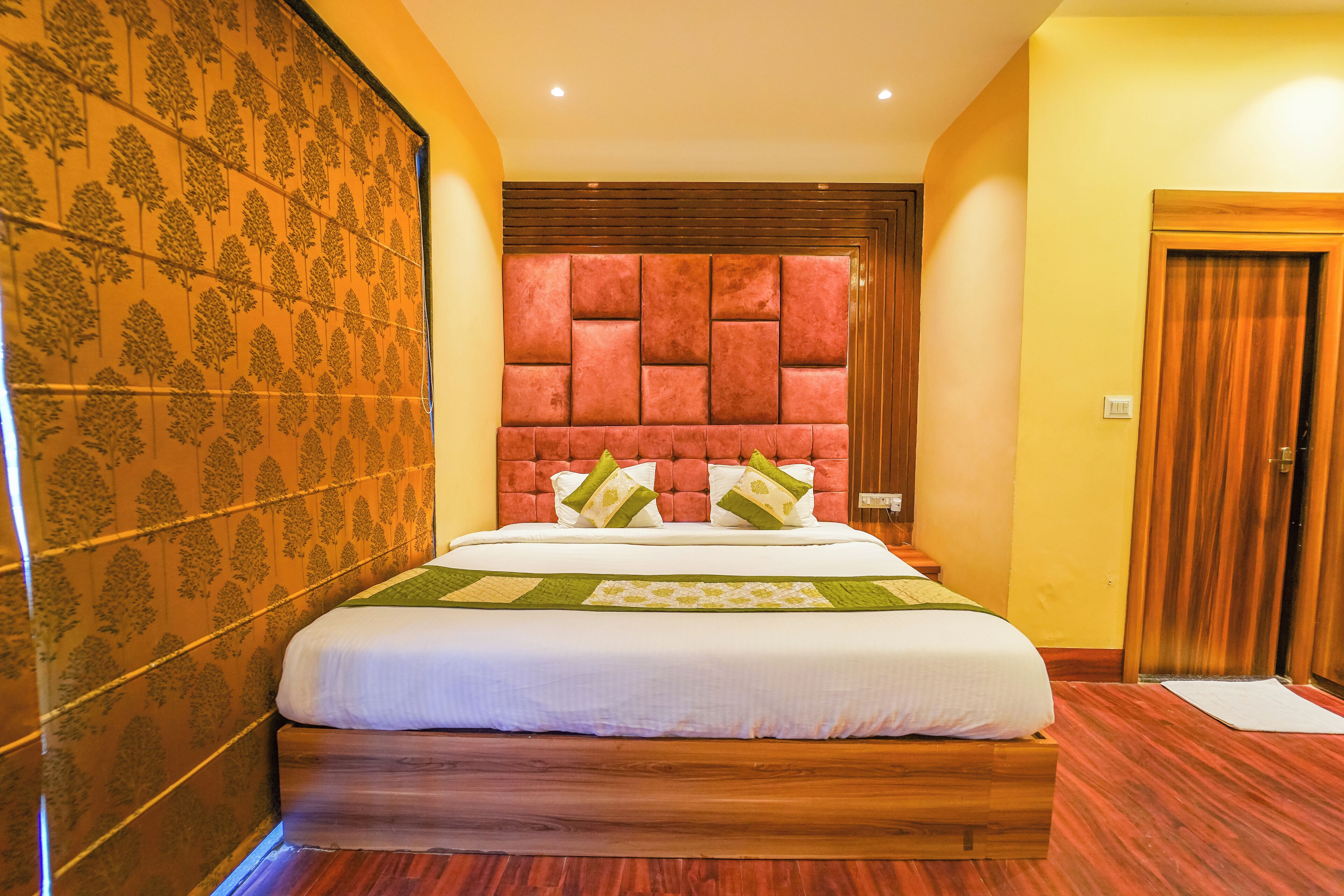 Une chambre d’hôtel avec un grand lit, une tête de lit en bois et un papier peint à motifs.