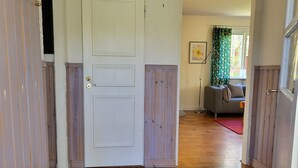 Un pasillo con una puerta blanca, paneles de madera y un tapete blanco.