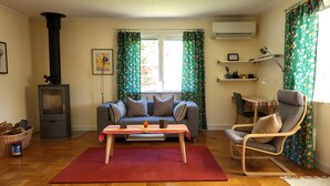 Un salón acogedor con un sofá, una mesa de centro, una silla, una chimenea y una ventana con cortinas.