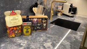 A kitchen with a marble countertop, a sink, and various food items including pasta and chocolate.