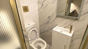 A modern bathroom with a toilet, sink, and mirror.