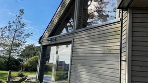 Une maison moderne dotée de grandes fenêtres et d’un toit en pente.