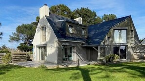 Une maison moderne à deux étages, dotée d ’un toit en pente, de grandes fenêtres et d’une pelouse bien entretenue.