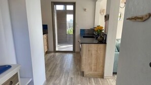 Une cuisine moderne avec des meubles en bois, un plan de travail et une porte-fenêtre coulissante donnant sur une terrasse.