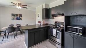 A modern kitchen with dark cabinetry, a built-in stove, and a microwave.