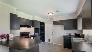 A modern kitchen with dark cabinetry, a central island, a microwave, and a sink.
