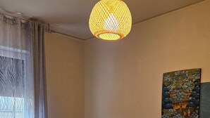 Habitación de hotel con dos camas, una silla, un cuadro y una lámpara colgante.