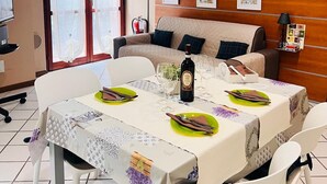 A dining area with a table set for four, a sofa, and a wall-mounted cabinet. - Mattia House within walking distance of the Center  (Lucca)