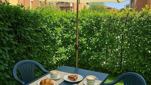 A table with a beige umbrella, two chairs, and plates with croissants and coffee cups. - Mattia House within walking distance of the Center  (Lucca)
