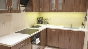 A kitchen with wooden cabinets, a white countertop, a built-in oven, and a coffee maker.