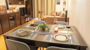 A dining area with a table set for four, including plates, cutlery, and glasses of red wine.