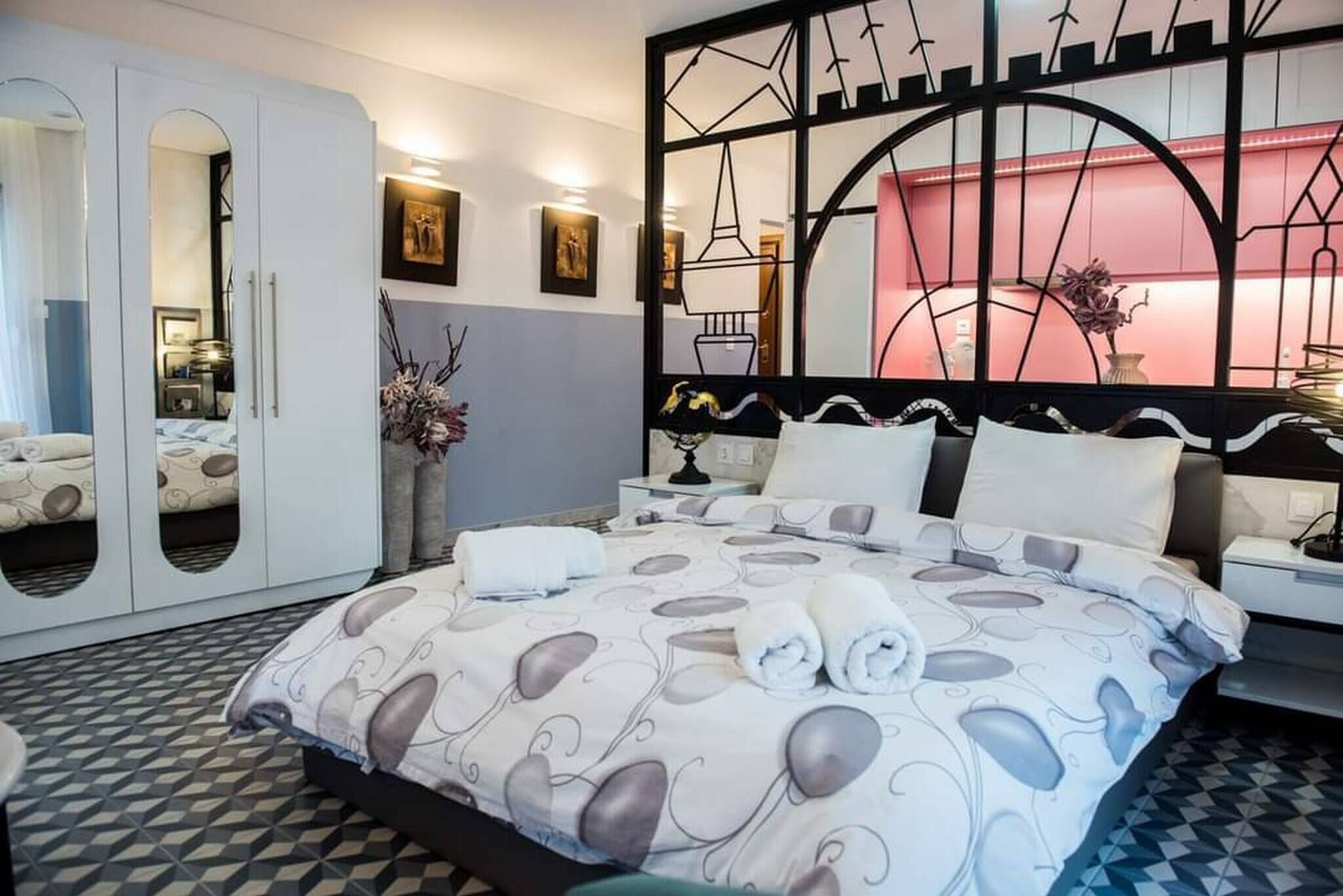 Een hotelkamer met een bed, een kast, een nachtkastje en een spiegel.