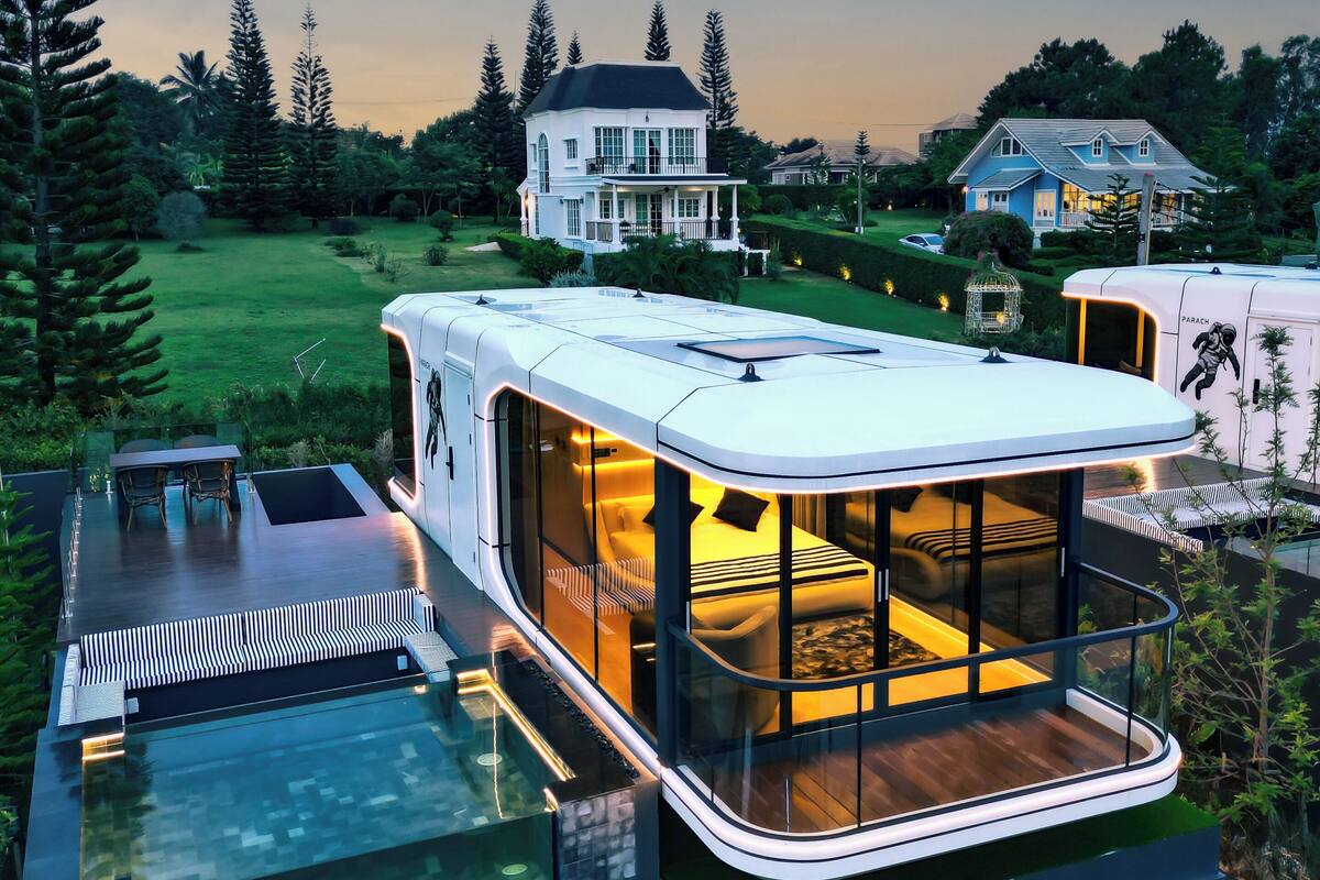A modern houseboat with a glass enclosure, a swimming pool, and a well-maintained garden.