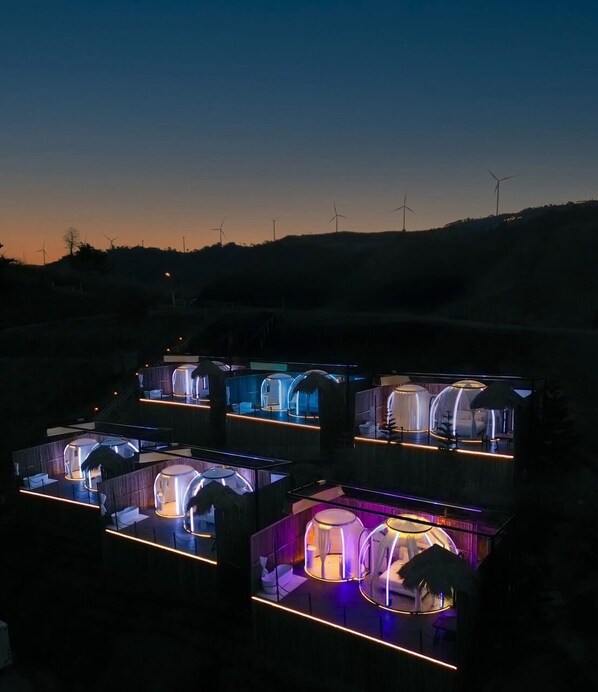A series of dome-shaped, illuminated pods arranged in a row, likely serving as accommodation units. - PARACH RESORT KHAOKHO (Khao Kho)