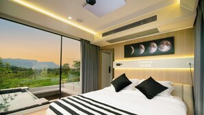 A modern hotel room with a large bed, a view of the countryside, and a wall-mounted artwork of the moon phases. - PARACH RESORT KHAOKHO (Khao Kho)