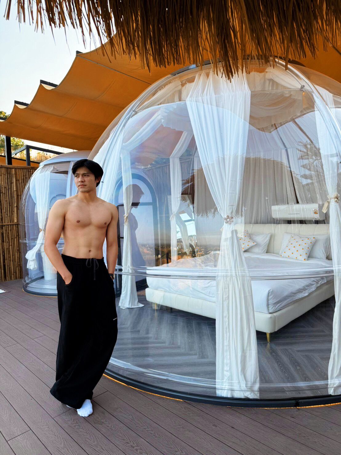 Estructura de cúpula transparente con una cama en su interior, rodeada de cortinas blancas.