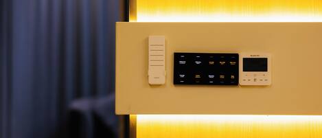 A control panel with a thermostat and a digital display, likely for room temperature control, mounted on a wall with a wooden finish.