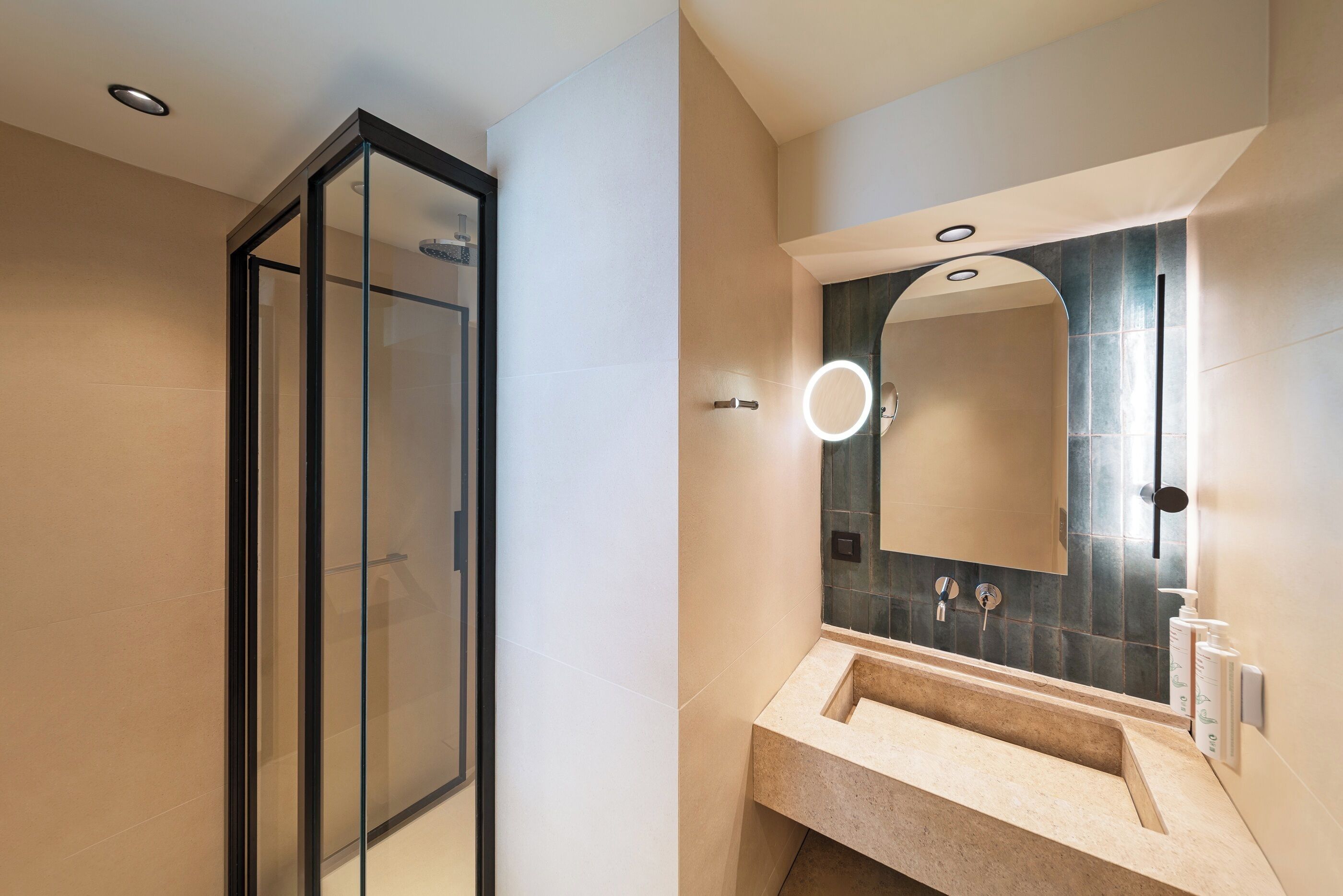 Un baño moderno con cabina de ducha de vidrio, lavamanos con espejo y aplique de pared.
