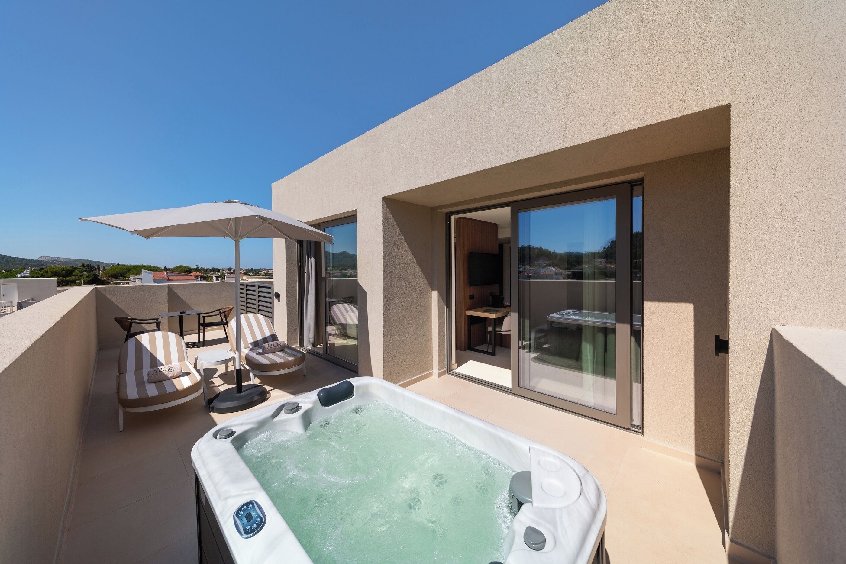 Terraza en la azotea con jacuzzi, sillones de descanso y puerta de vidrio que da a un espacio interior.