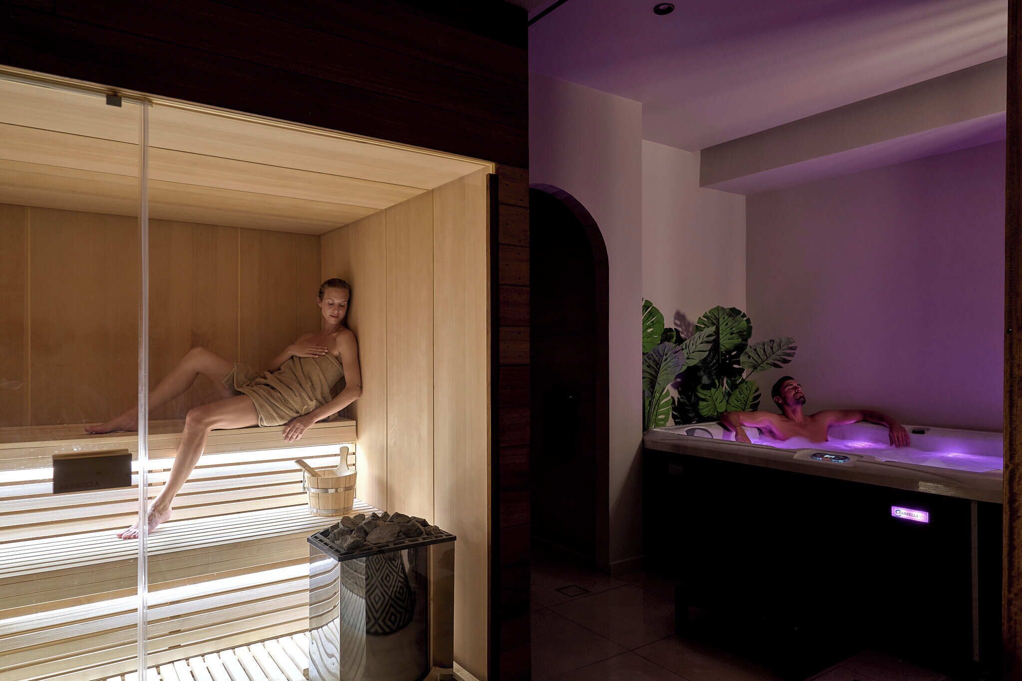 A sauna room with a wooden bench and a person sitting on it.