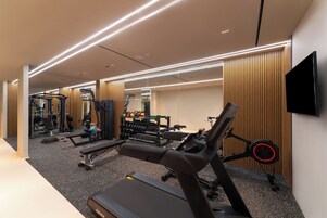 Un gimnasio moderno con cintas de correr, máquinas de pesas y un espejo grande.