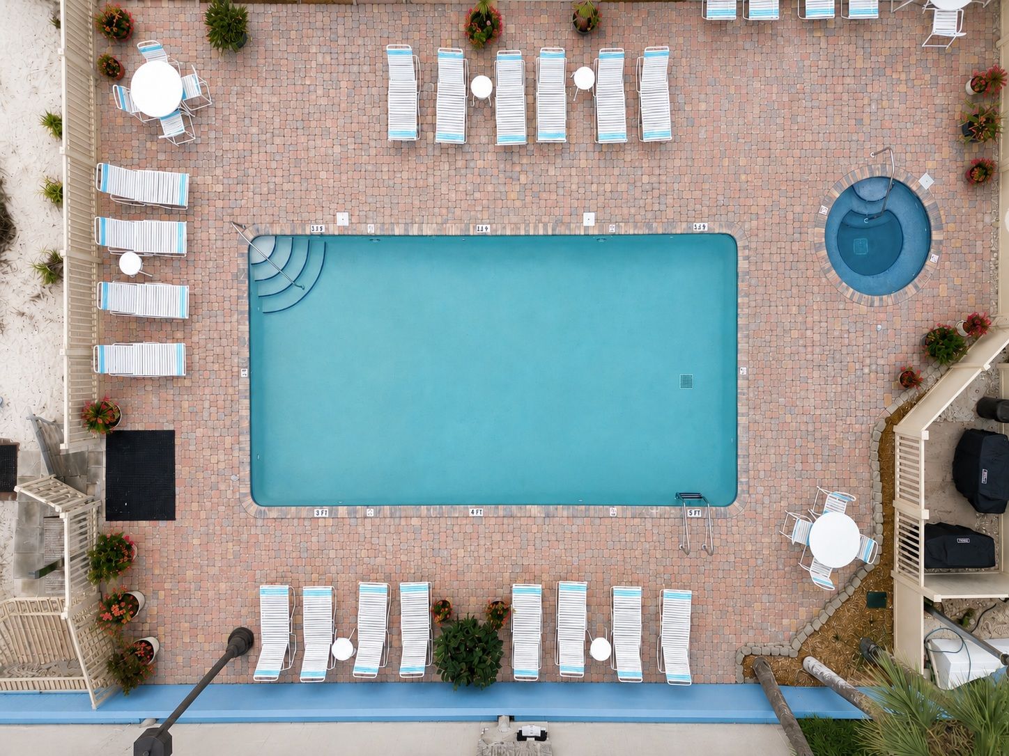 A rooftop swimming pool with lounge chairs and tables arranged around it.