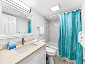 A modern bathroom with a large mirror, a sink, a toilet, and a shower area.